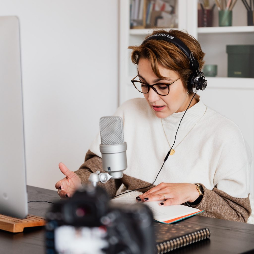 mujer con auriculares y micrófono frente a una computadora
